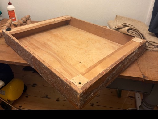A bare jointed timber frame on the workbench, with turned legs and glue waiting beside it