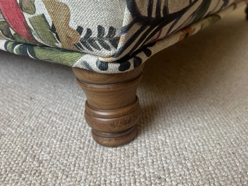 A hand-folded corner of printed linen sitting above a turned wooden leg